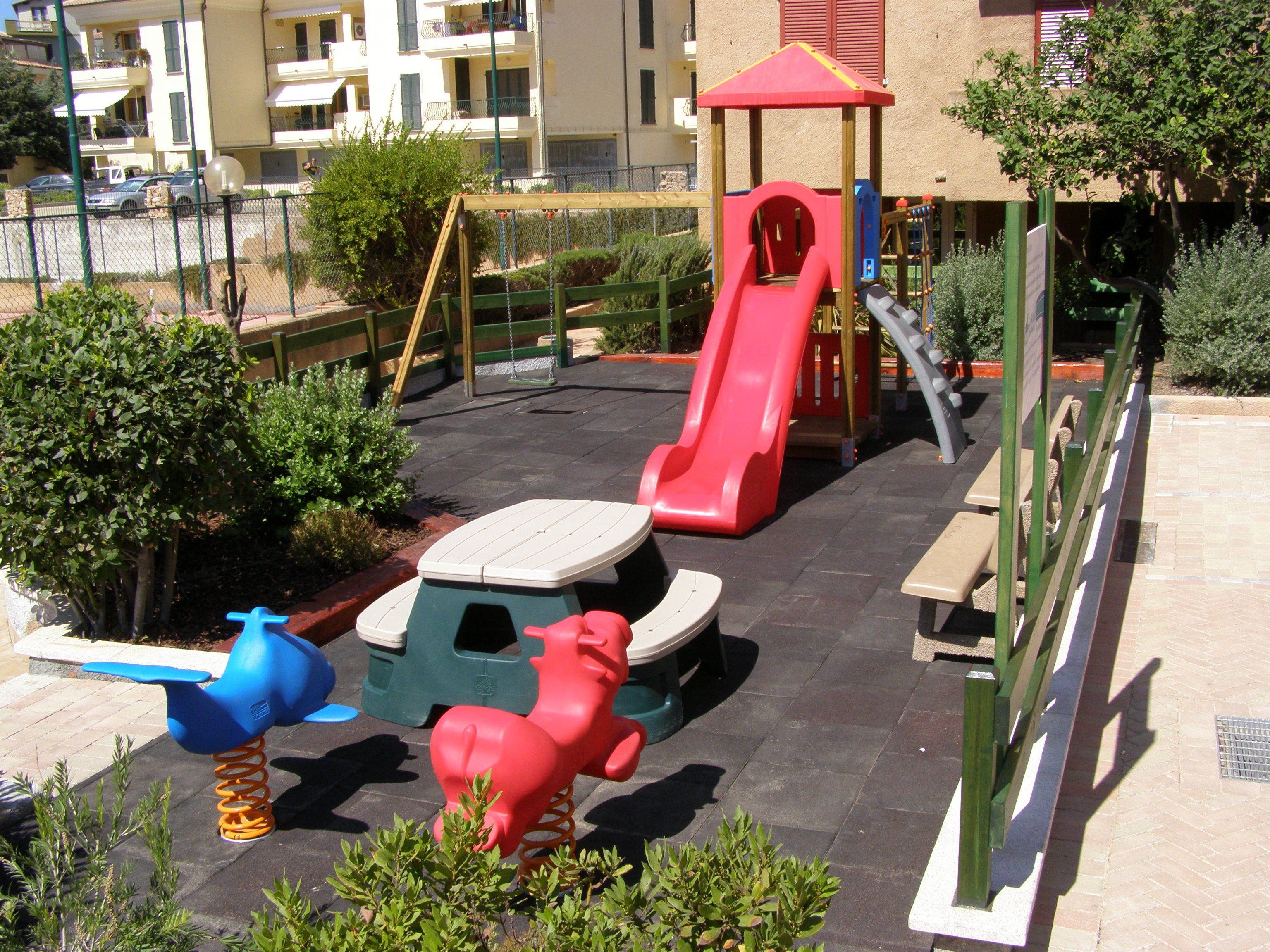 Ein Kinderspielplatz mit Rutsche, Schaukeln und einer Kletterkonstruktion.