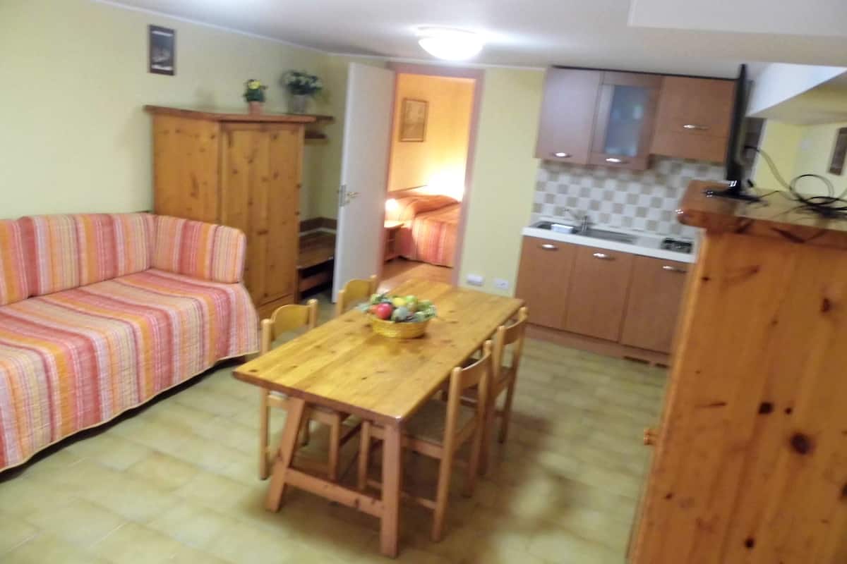Un espacio habitable compacto con una mesa de comedor de madera, un sofá a rayas y una kitchenette.