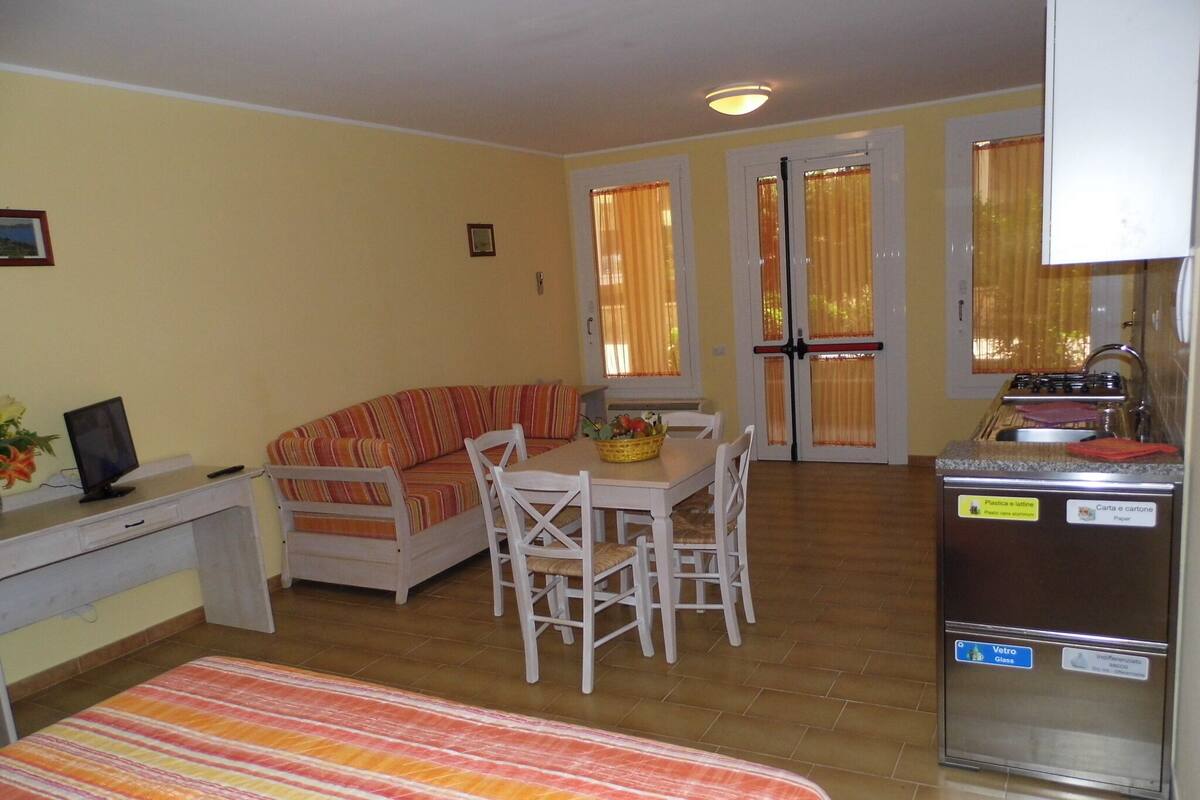 Un espacio habitable compacto con sofá, mesa de comedor y kitchenette.