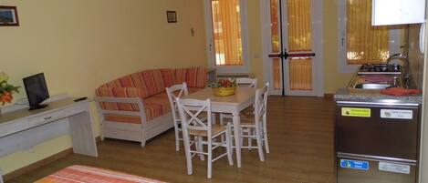 A compact living space with a sofa, dining table, and a kitchenette.