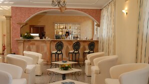 Zona de bar amb barra, tamborets i seients amb butaques blanques i taules.