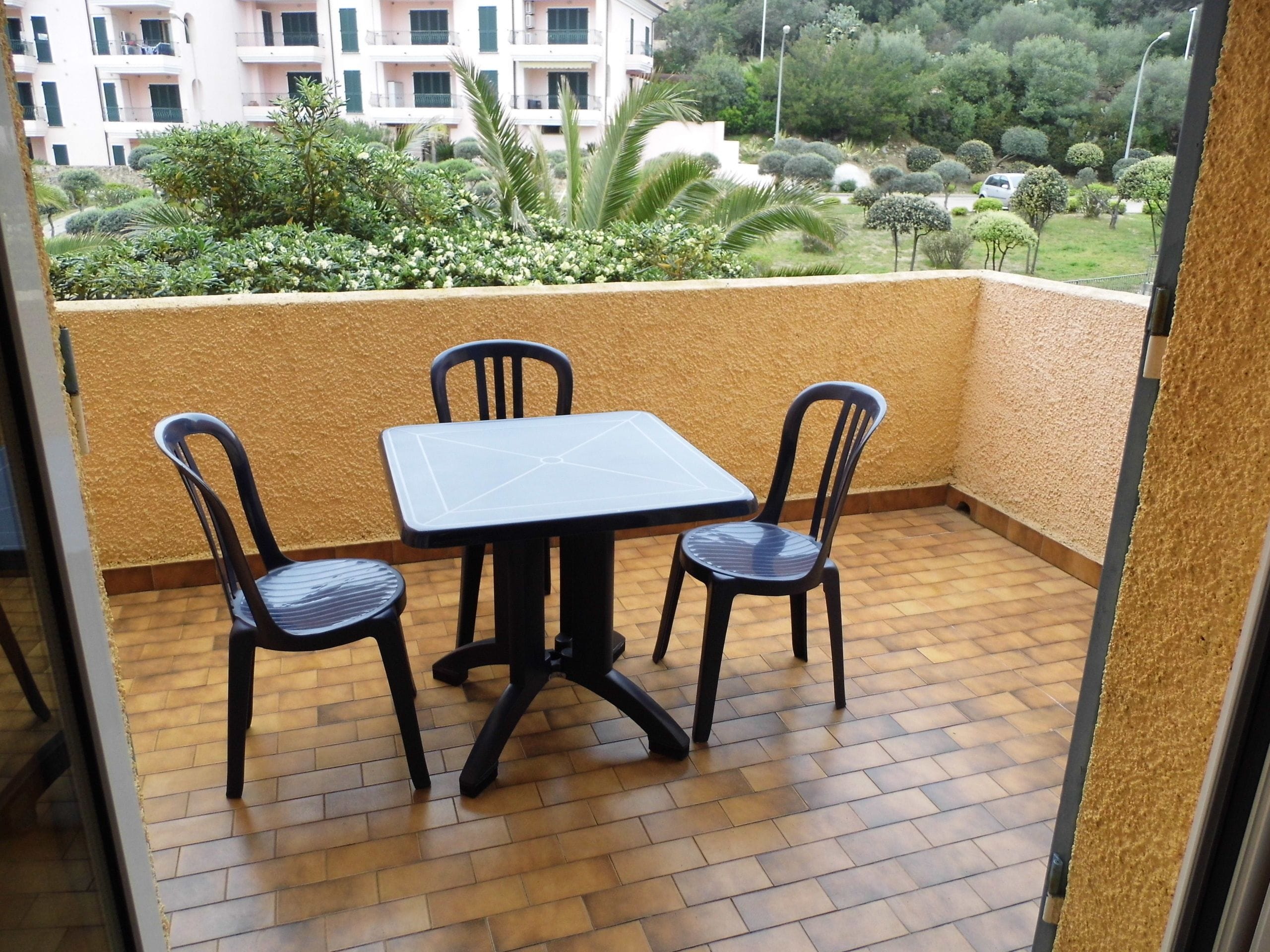 A balcony with a tiled floor and two chairs and a table.
