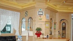 Un vestíbulo con una mesa de recepción, un sofá y una planta decorativa.