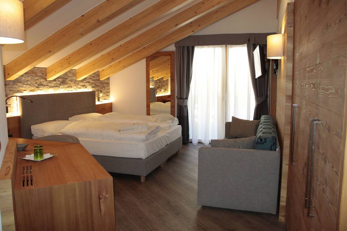 Un dormitorio con cama, un escritorio de madera, una silla y una pared de piedra.