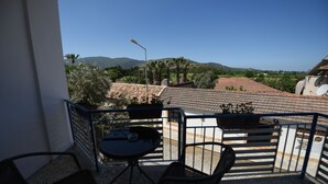 A balcony with a table and chairs, overlooking a residential area with houses and hills. - Rebetika Hotel (Selçuk)