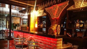 A bar area with a brick wall, a large wine barrel, and several stools. - Rebetika Hotel (Selçuk)
