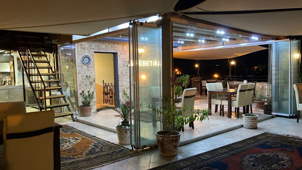 A modern interior with a glass partition, a staircase, and a dining area with chairs and tables. - Rebetika Hotel (Selçuk)