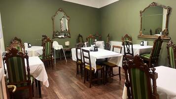 Comedor con paredes verdes, sillas de madera y mesas dispuestas para comer.