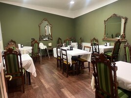 Comedor con paredes verdes, sillas de madera y mesas dispuestas para comer.