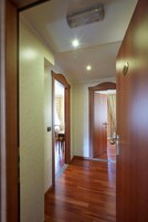 Un pasillo con suelo de madera y puertas que dan a varias habitaciones.
