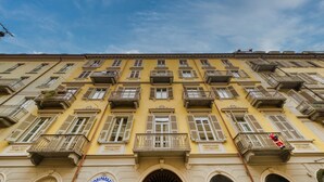 Un edificio de varios pisos con fachada amarilla, múltiples balcones y un cielo azul despejado.