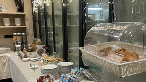 Montaje de bufé con diversos alimentos, como pasteles y salsas, exhibidos sobre una mesa con mantel blanco.