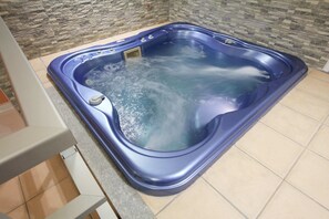 A hot tub with a stone wall backdrop and tiled flooring. - Hotel Liberty (Turin)