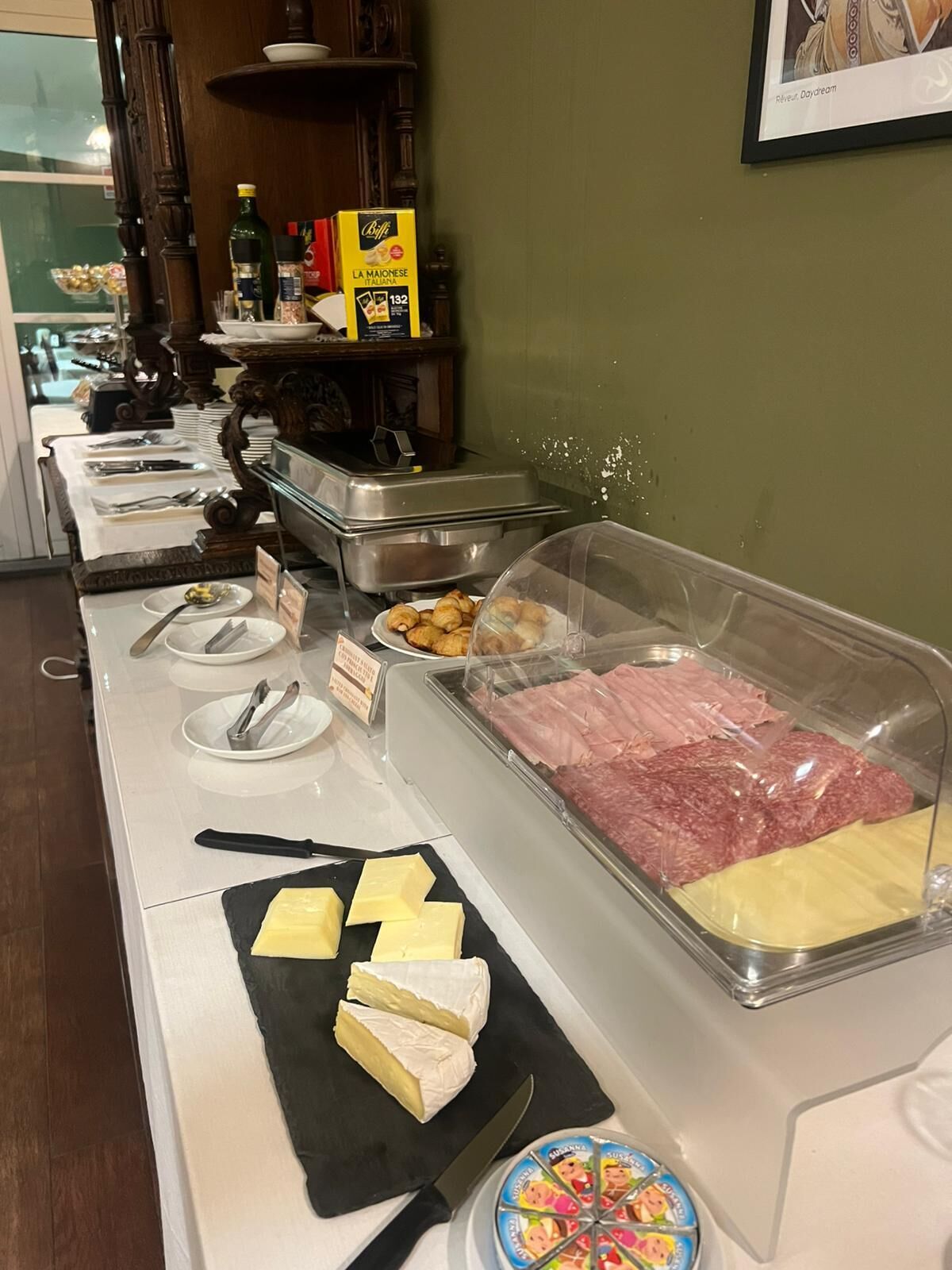 A buffet setup with various food items including meats, cheeses, and pastries.