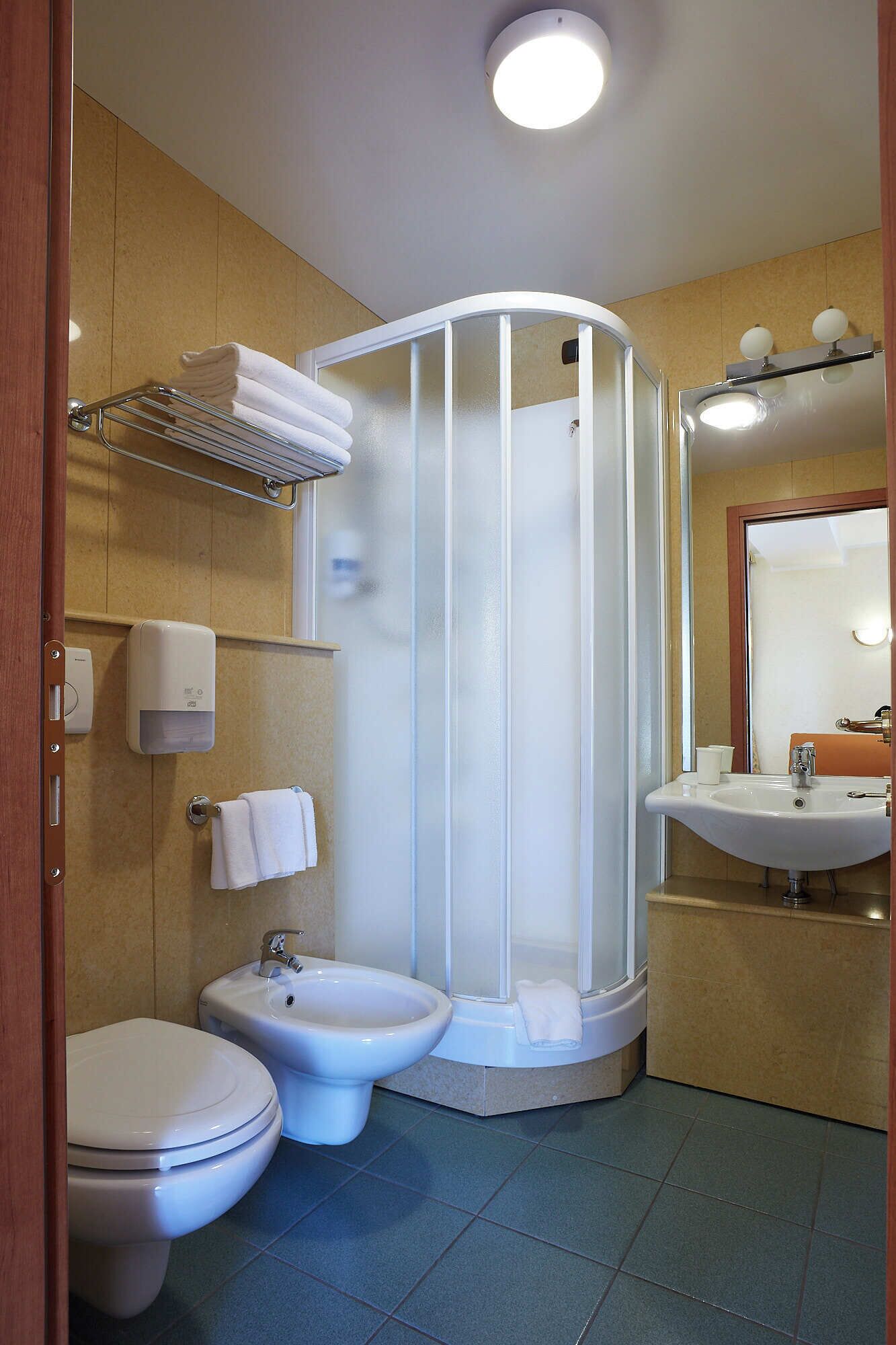 A bathroom with a shower enclosure, toilet, bidet, and sink.