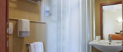 A bathroom with a shower enclosure, toilet, bidet, and sink.