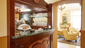 Una zona de bar con un expositor de vidrio, una máquina de café y un área de descanso con dos sillones.