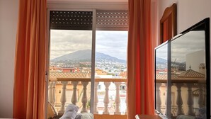 A hotel room with a balcony, a bed with towels, and a TV. - Hostal San Felipe (Marbella)