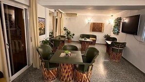 A dining area with a table and chairs, a TV mounted on the wall, and a door leading to another room. - Hostal San Felipe (Marbella)