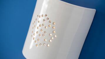 A white mug with gold-colored holes on a blue background.