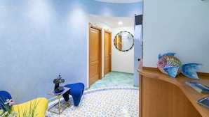 A room with a curved ceiling, a blue and white patterned floor, a wooden reception desk, and a colorful fish decoration. - La Casa delle Stelle (Maiori)