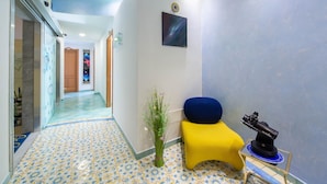 A hallway with patterned floor tiles, a yellow bench, a telescope, and a wall-mounted picture. - La Casa delle Stelle (Maiori)
