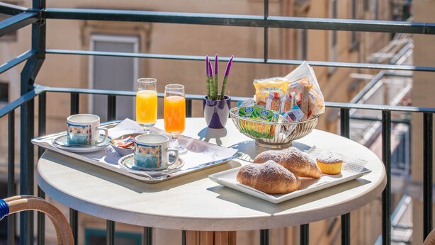 A balcony with breakfast items including pastries, juice, and a fruit basket. - La Casa delle Stelle (Maiori)