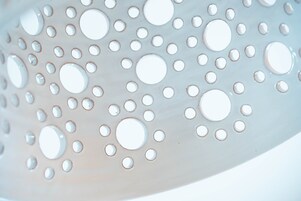 Primer plano de una superficie metálica perforada con agujeros circulares.