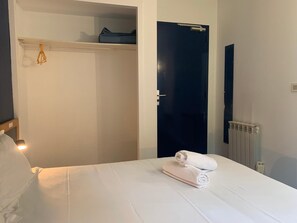 A hotel room with a bed, a wardrobe, a door, and a radiator. - Hôtel Montilleul (Pau)