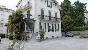 A two-story building with a balcony, a staircase leading to the entrance, and potted plants. - Hôtel Montilleul (Pau)