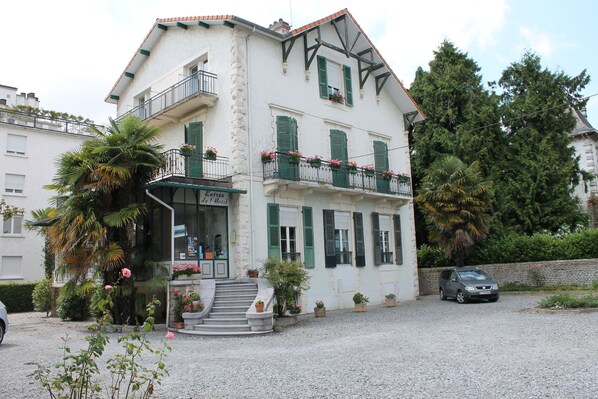A two-story building with a balcony, a staircase leading to the entrance, and potted plants. - Hôtel Montilleul (Pau)