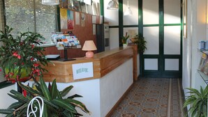 A hotel reception area with a wooden counter, a sign reading "HOTEL DE LOUVRE," and various plants. - Hôtel Montilleul (Pau)
