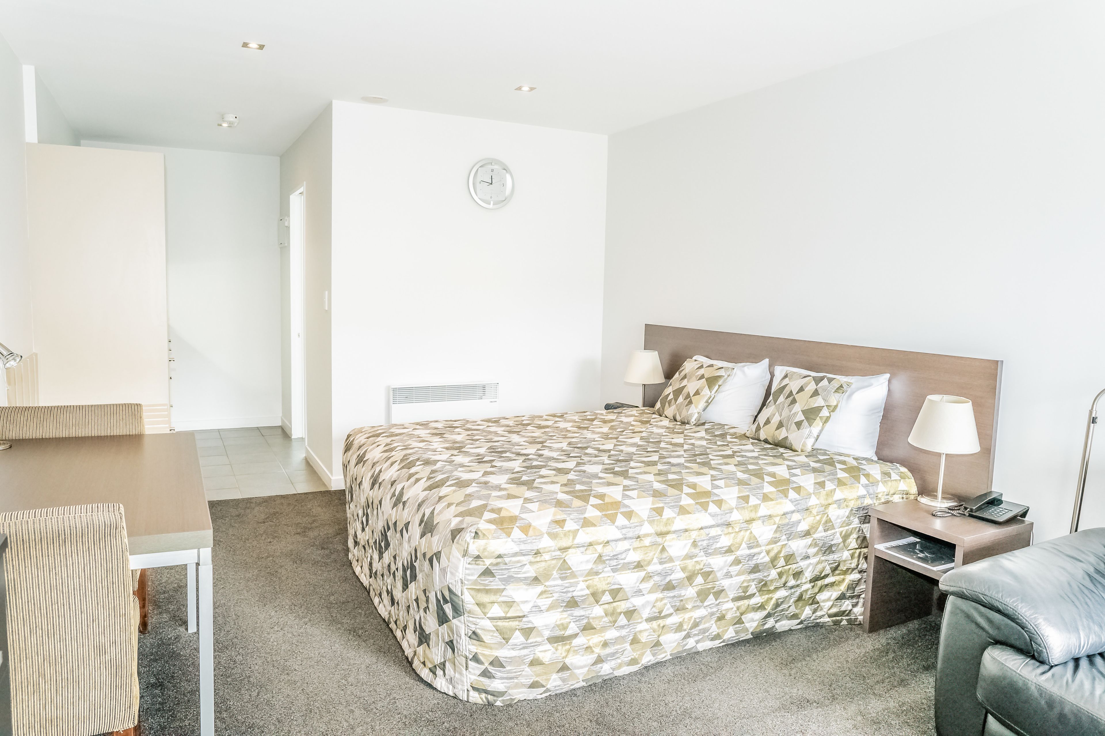 Una habitación de hotel con cama, mesita de noche, lámpara y una silla.
