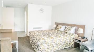 Una habitación de hotel con cama, mesita de noche, lámpara y una silla.