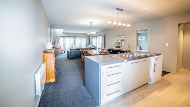 Una cocina moderna con una isla central, una zona de comedor con una mesa y sillas, y una sala de estar con un sofá y una mesita de centro.