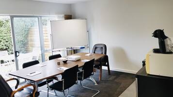 Una sala de reuniones moderna con una gran mesa, sillas, una pizarra y un proyector.