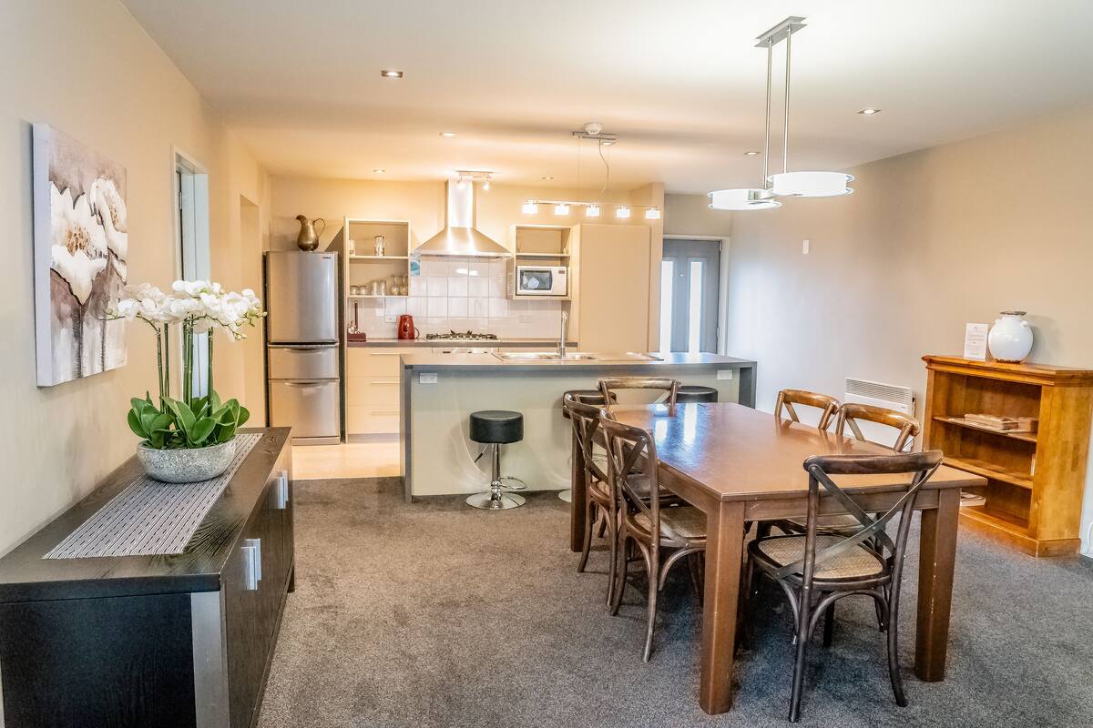 A modern kitchen with a central island, dining table, and chairs.