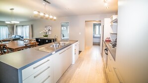 Una cocina moderna con una isla central, electrodomésticos integrados y un comedor con mesa y sillas de madera.