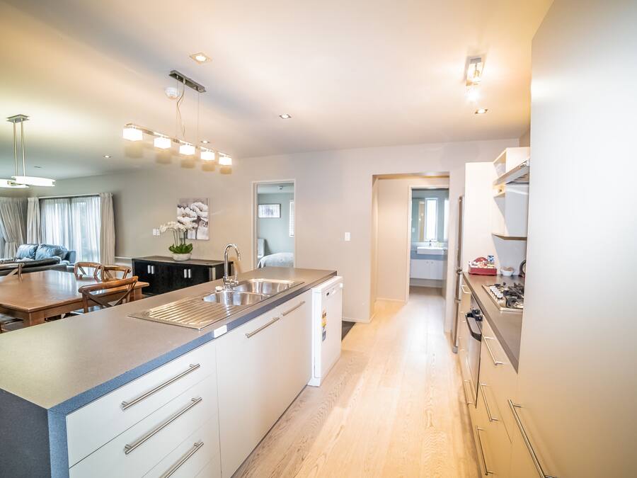 A modern kitchen with a central island, built-in appliances, and a dining area with a wooden table and chairs.