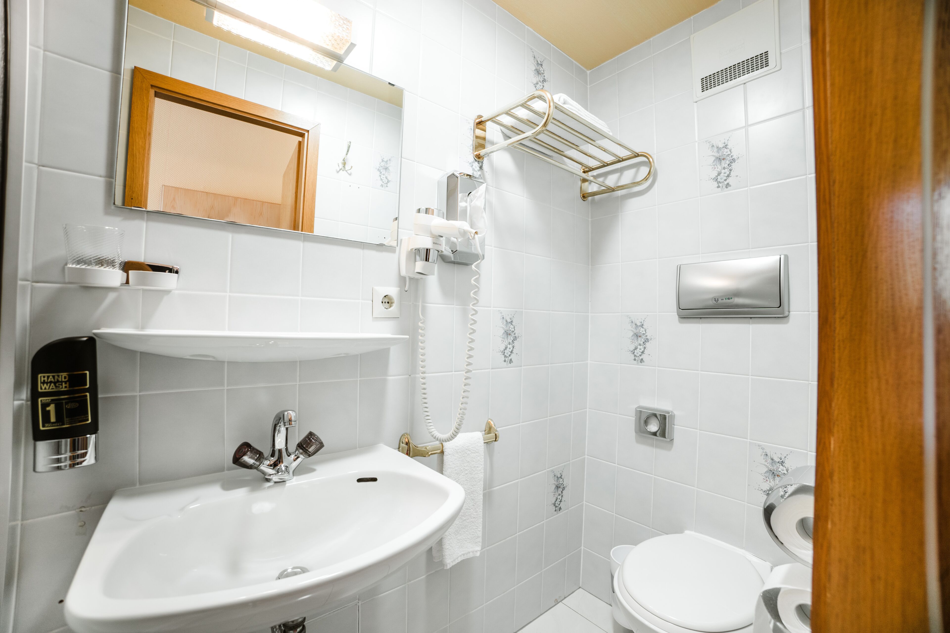 A bathroom with a sink, toilet, towel rack, and a mirror.