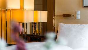 Habitación de hotel con cama, mesita de noche, lámpara e interruptor de luz en la pared.