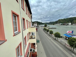 A hotel with a balcony, a view of a river, and a sign for 'Hotel Rheinwald'.