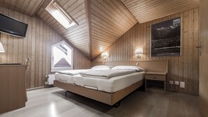 A wooden-paneled bedroom with a bed, bedside table, lamp, and a poster on the wall. - Hotel Rössli (Unterseen)