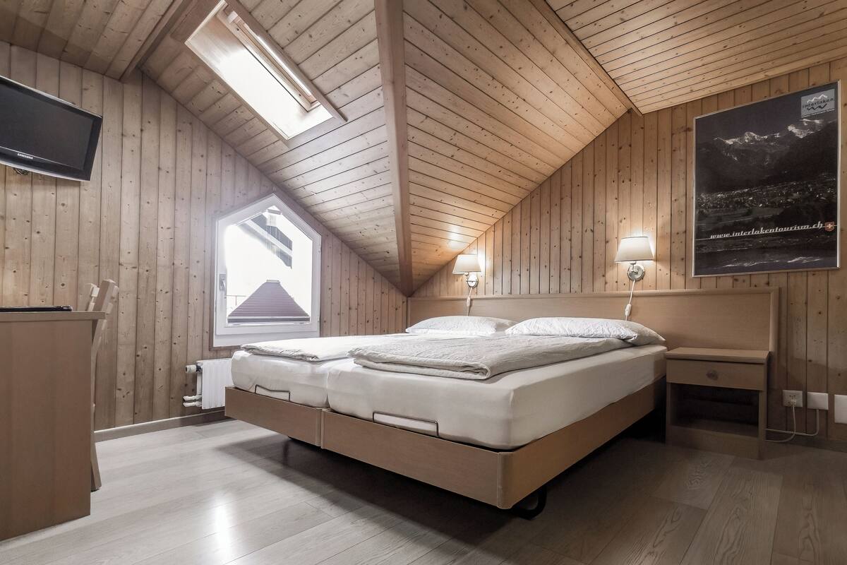 Un dormitorio con paneles de madera, una cama, mesita de noche, lámpara y un cartel en la pared.