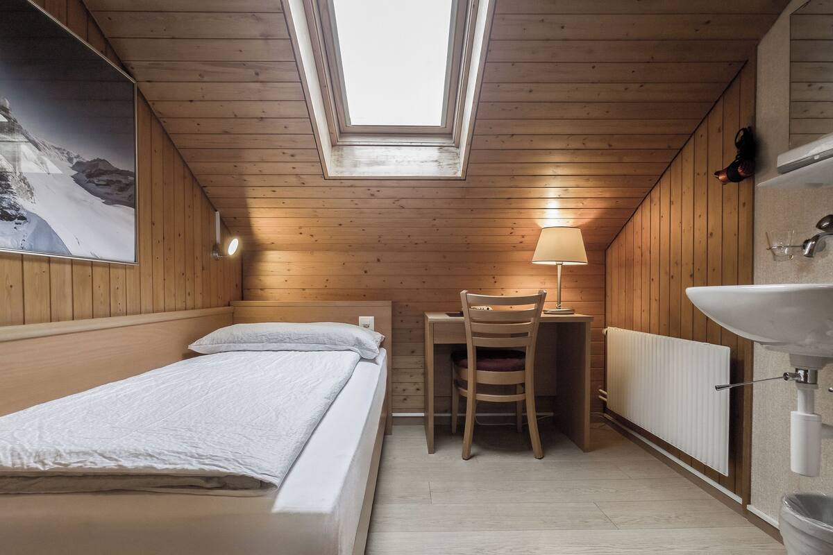 Una habitación pequeña y acogedora con una cama, un escritorio y un baño.