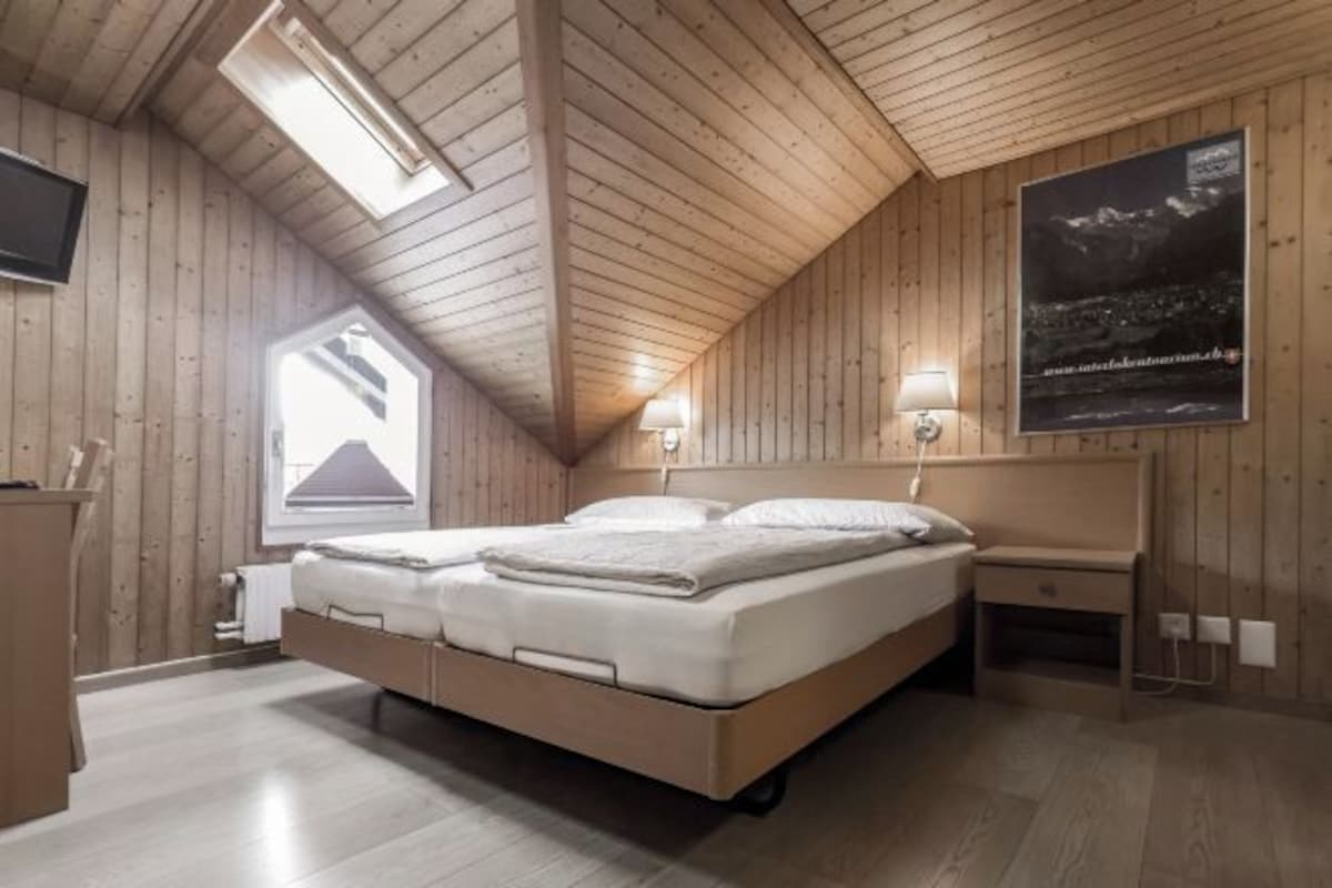 A wooden-paneled room with a bed, a nightstand, and a poster on the wall.
