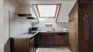 A compact kitchen with a built-in microwave, a sink, and wooden cabinets. - Hotel Rössli (Unterseen)