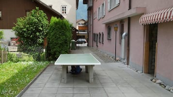 Une cour avec une table de ping-pong, entourée de bâtiments et de verdure.