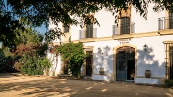 Stately Hacienda de S. Rafael features a symmetrical facade with a central doorway and lush greenery surroundings.