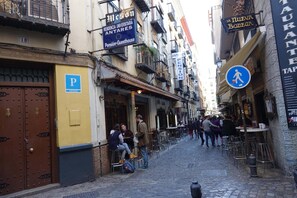 A narrow street with outdoor seating areas, a pension guesthouse, and a restaurant. - Hostal Pensión Antares (Granada)